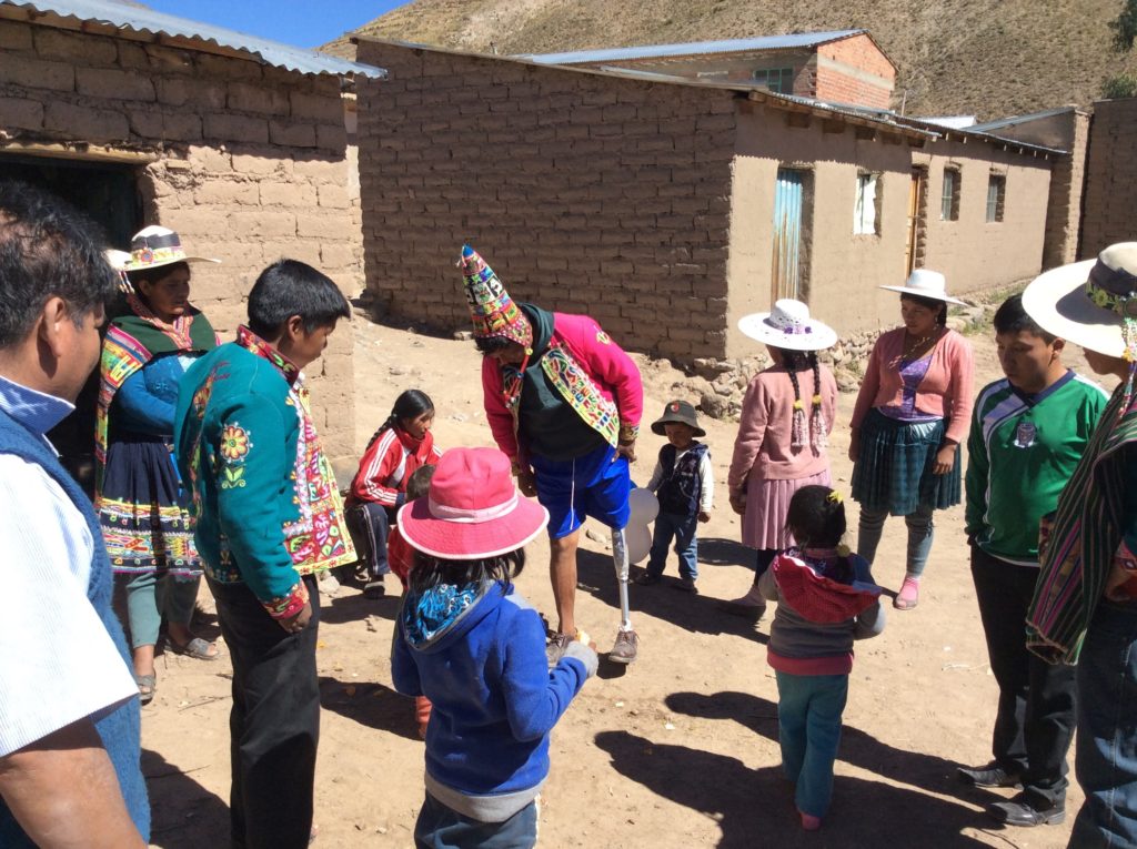 Augustine walking on his new leg while other villagers watch