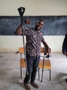 Man with new leg raising his old crutch in celebration of his new found mobility