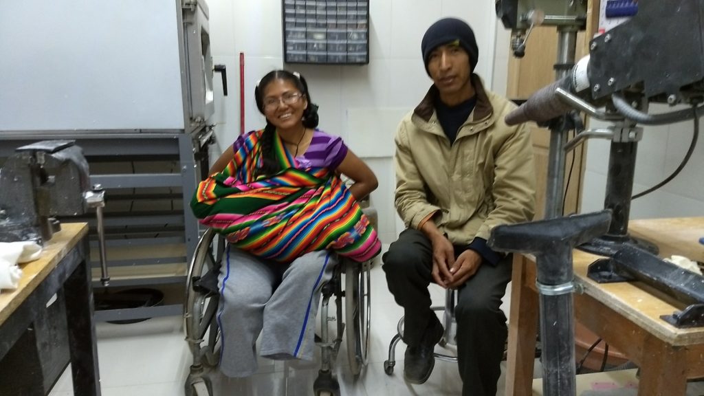 Martha holding her baby daughter in her wheelchair with her husband sitting beside her