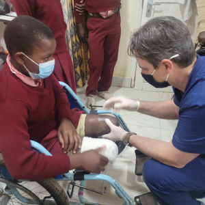 Steve looking at young girls legs to evaluate for fitting prothesis